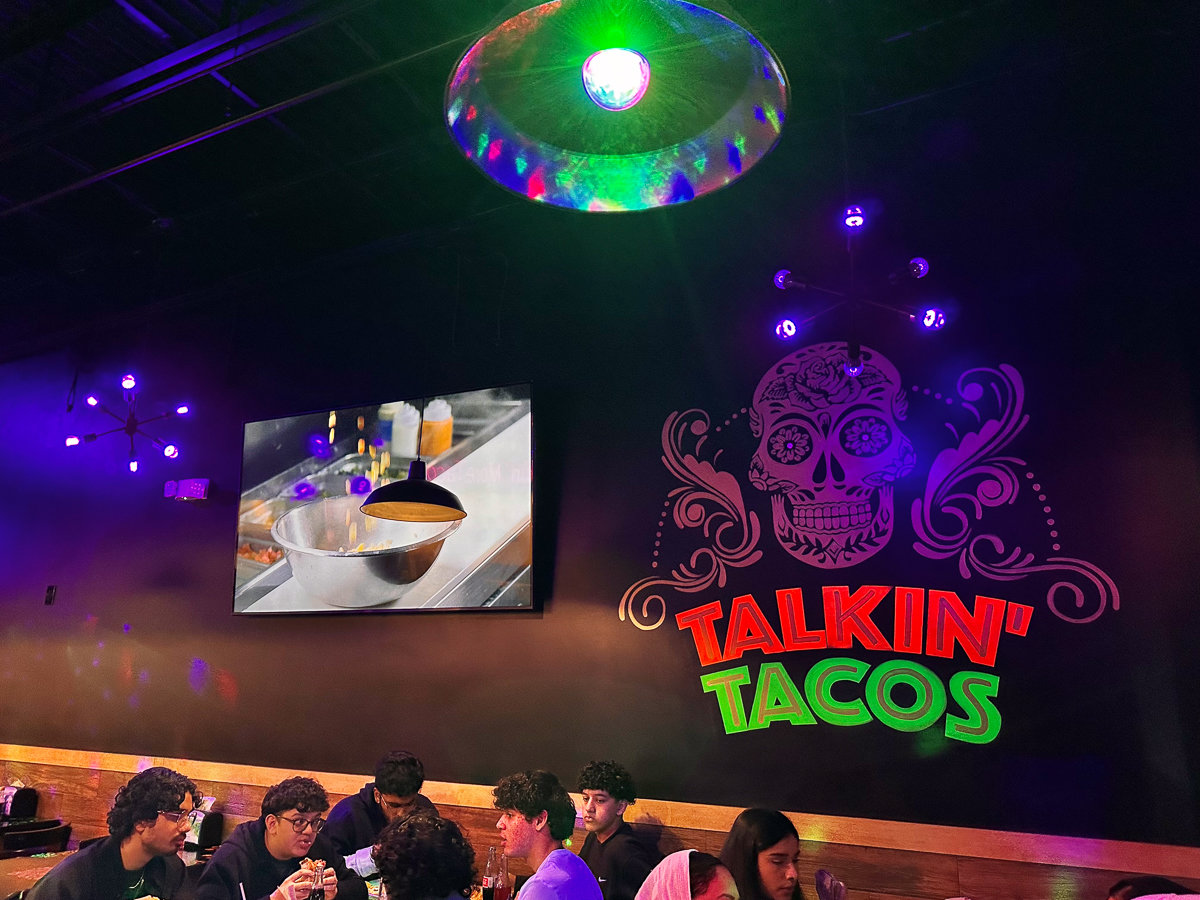 black wall with neon talkin tacos mural